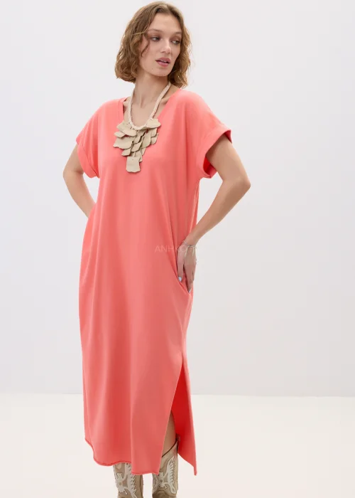 Koralowa sukienka maxi o luźnym, oversize’owym kroju z krótkim rękawem i dekoltem w serek, zestawiona z kowbojkami w stylizacji casual boho.
