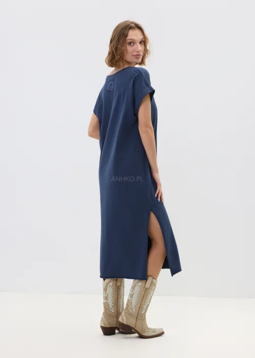Granatowa sukienka midi o luźnym, oversize’owym kroju z krótkim rękawem i dekoltem w serek, zestawiona z kowbojkami i długim naszyjnikiem w stylizacji casual.