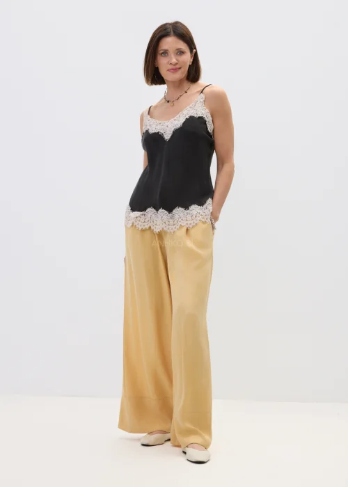 Czarny top damski na cienkich ramiączkach z delikatnym koronkowym wykończeniem przy dekolcie i dole, o lekkim, satynowym wykończeniu, stylizacja w eleganckim, kobiecym klimacie.
