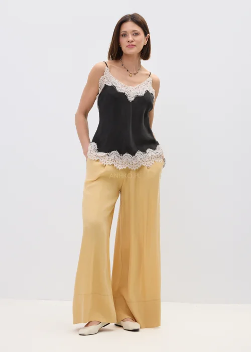 Czarny top damski na cienkich ramiączkach z delikatnym koronkowym wykończeniem przy dekolcie i dole, o lekkim, satynowym wykończeniu, stylizacja w eleganckim, kobiecym klimacie.