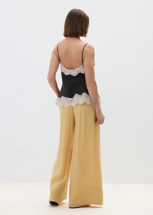 Czarny top damski na cienkich ramiączkach z delikatnym koronkowym wykończeniem przy dekolcie i dole, o lekkim, satynowym wykończeniu, stylizacja w eleganckim, kobiecym klimacie.