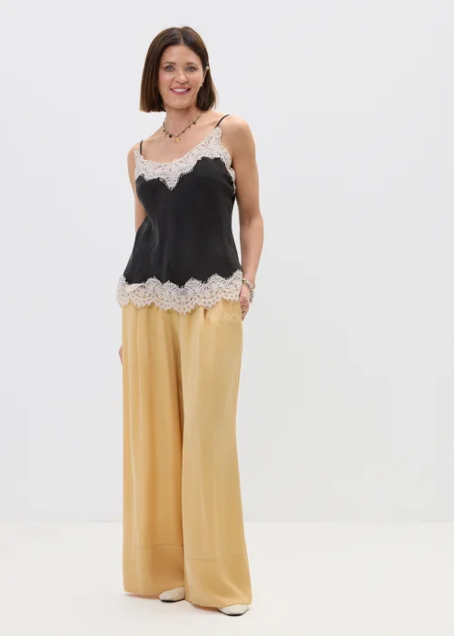 Czarny top damski na cienkich ramiączkach z delikatnym koronkowym wykończeniem przy dekolcie i dole, o lekkim, satynowym wykończeniu, stylizacja w eleganckim, kobiecym klimacie.