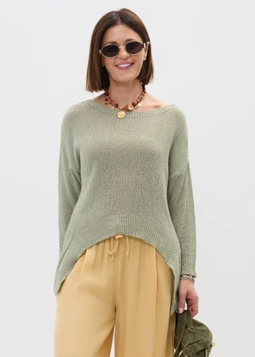 Szałwiowy sweter damski oversize z asymetrycznym dołem  stylizowany z luźnymi spodniami w casualowym looku.