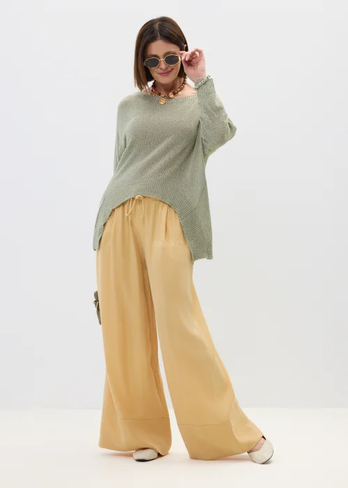 Szałwiowy sweter damski oversize z asymetrycznym dołem  stylizowany z luźnymi spodniami w casualowym looku.