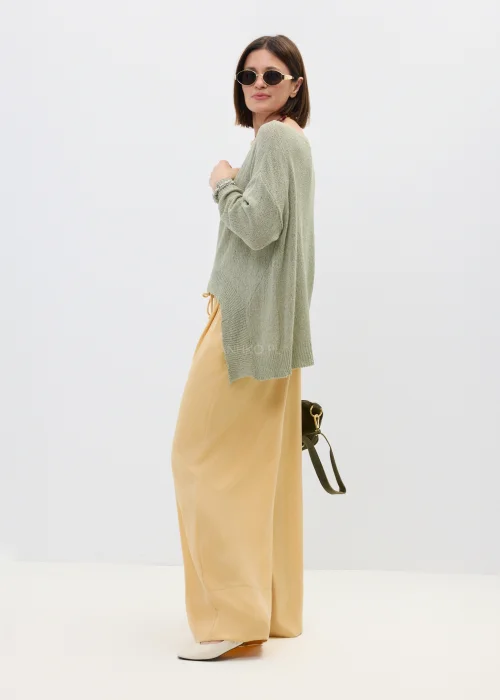 Szałwiowy sweter damski oversize z asymetrycznym dołem  stylizowany z luźnymi spodniami w casualowym looku.