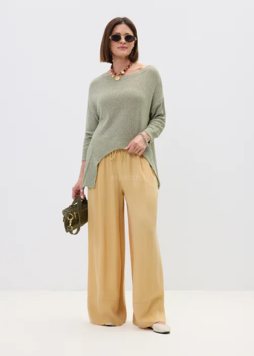 Szałwiowy sweter damski oversize z asymetrycznym dołem  stylizowany z luźnymi spodniami w casualowym looku.