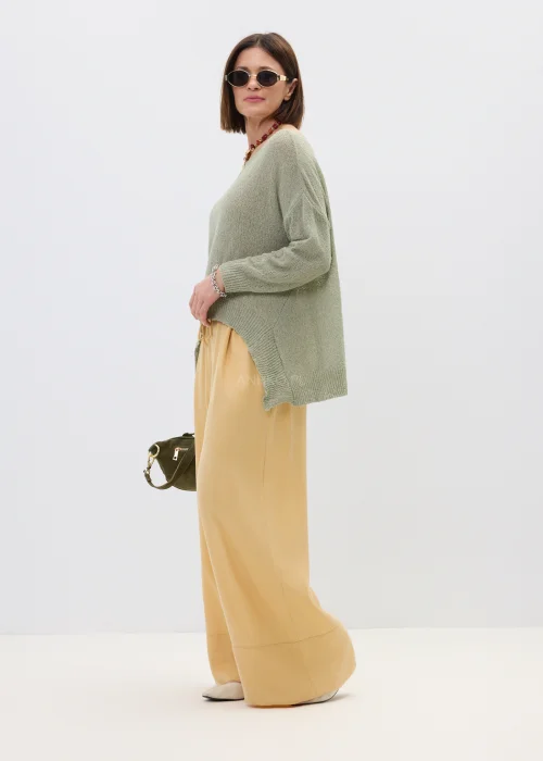 Szałwiowy sweter damski oversize z asymetrycznym dołem  stylizowany z luźnymi spodniami w casualowym looku.