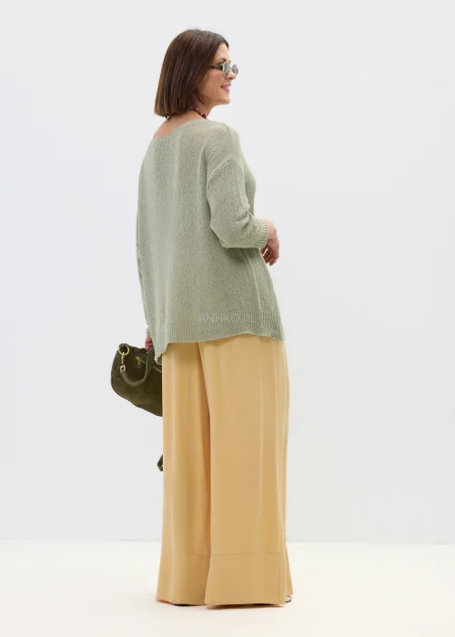 Szałwiowy sweter damski oversize z asymetrycznym dołem  stylizowany z luźnymi spodniami w casualowym looku.