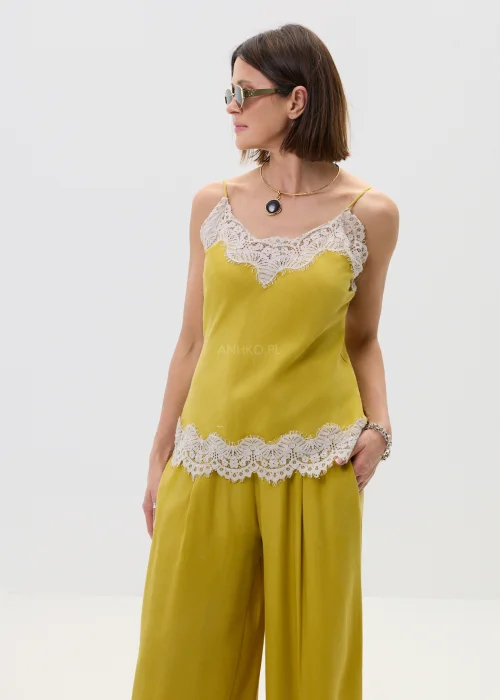 Żółty top damski na ramiączkach z koronkowym wykończeniem przy dekolcie i dole, lekki i elegancki, stylizowany z szerokimi spodniami w dopasowanym looku.