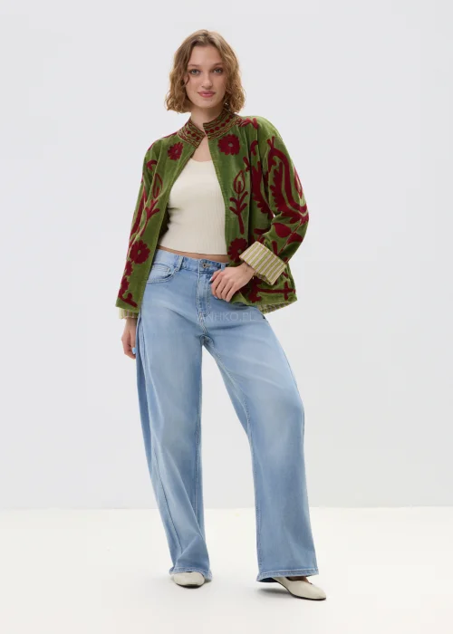 Zielony żakiet z bordowym haftem roślinnym, krótki fason ze stójką i podwiniętymi rękawami w paski, stylizowany z jasnymi jeansami.