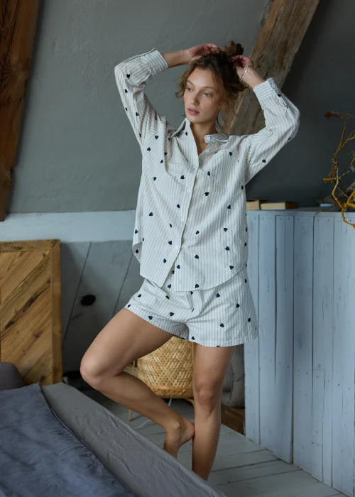 Piżama damska dwuczęściowa w kolorze ecru w delikatne paski i drobne serduszka, koszula zapinana na guziki i krótkie spodenki z luźnym, komfortowym krojem.
