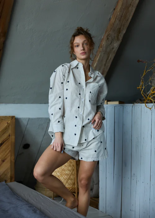 Piżama damska dwuczęściowa w kolorze ecru w delikatne paski i drobne serduszka, koszula zapinana na guziki i krótkie spodenki z luźnym, komfortowym krojem.