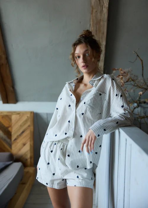 Piżama damska dwuczęściowa w kolorze ecru w delikatne paski i drobne serduszka, koszula zapinana na guziki i krótkie spodenki z luźnym, komfortowym krojem.