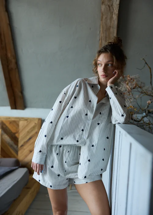 Piżama damska dwuczęściowa w kolorze ecru w delikatne paski i drobne serduszka, koszula zapinana na guziki i krótkie spodenki z luźnym, komfortowym krojem.