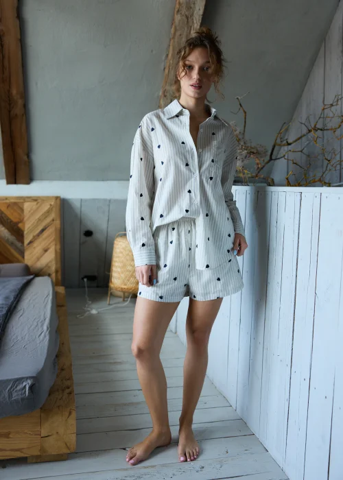 Piżama damska dwuczęściowa w kolorze ecru w delikatne paski i drobne serduszka, koszula zapinana na guziki i krótkie spodenki z luźnym, komfortowym krojem.