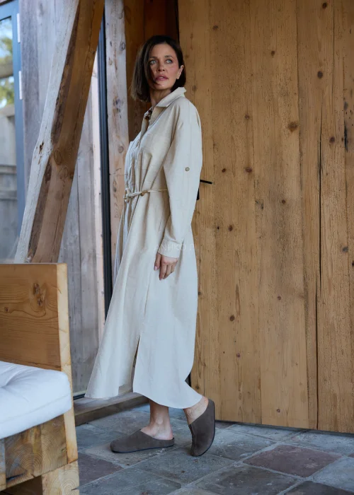 Beżowa sukienka koszulowa midi z dodatkiem lnu, z paskiem w talii, zapinana na guziki, z długim rękawem, minimalistyczna stylizacja casual.