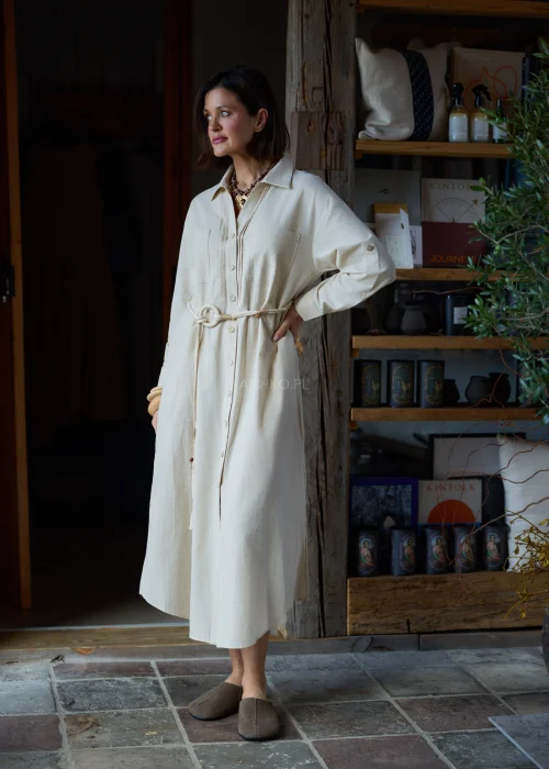 Beżowa sukienka koszulowa midi z dodatkiem lnu, z paskiem w talii, zapinana na guziki, z długim rękawem, minimalistyczna stylizacja casual.