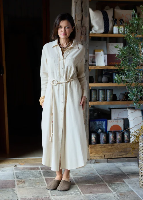 Beżowa sukienka koszulowa midi z dodatkiem lnu, z paskiem w talii, zapinana na guziki, z długim rękawem, minimalistyczna stylizacja casual.