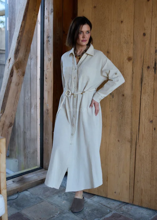 Beżowa sukienka koszulowa midi z dodatkiem lnu, z paskiem w talii, zapinana na guziki, z długim rękawem, minimalistyczna stylizacja casual.