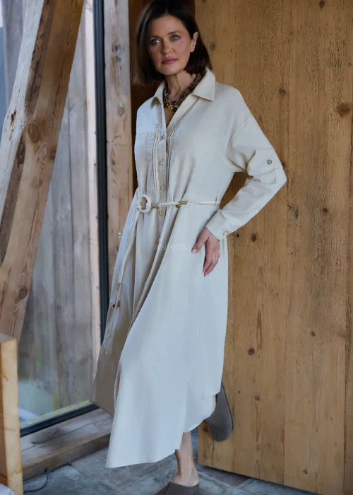 Beżowa sukienka koszulowa midi z dodatkiem lnu, z paskiem w talii, zapinana na guziki, z długim rękawem, minimalistyczna stylizacja casual.