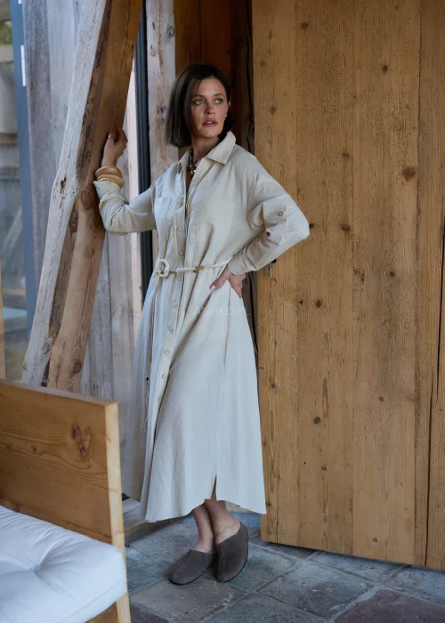 Beżowa sukienka koszulowa midi z dodatkiem lnu, z paskiem w talii, zapinana na guziki, z długim rękawem, minimalistyczna stylizacja casual.