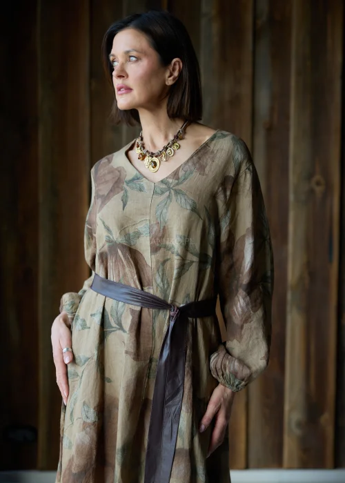 Brązowa sukienka lniana maxi w kwiatowy wzór z długim rękawem i paskiem w talii, luźny fason, styl naturalny i elegancki.