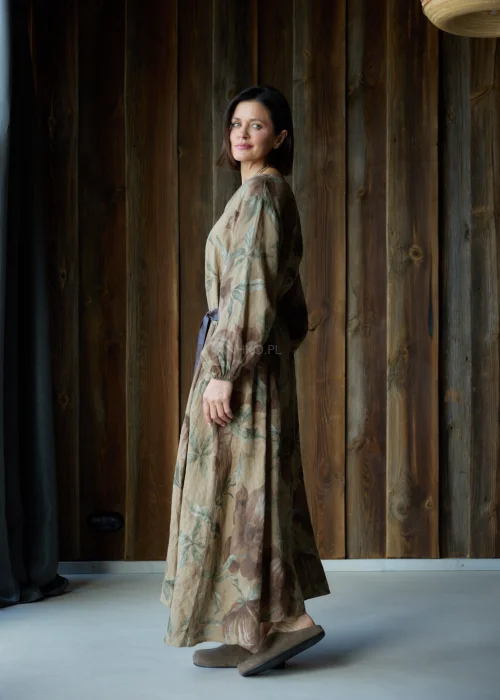 Brązowa sukienka lniana maxi w kwiatowy wzór z długim rękawem i paskiem w talii, luźny fason, styl naturalny i elegancki.