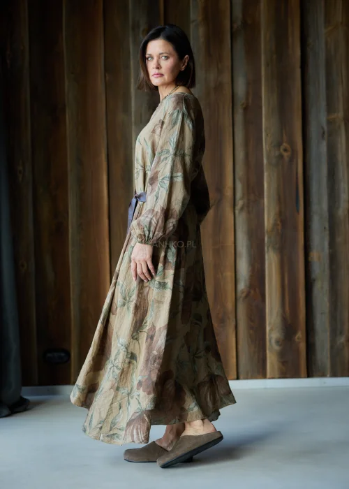 Brązowa sukienka lniana maxi w kwiatowy wzór z długim rękawem i paskiem w talii, luźny fason, styl naturalny i elegancki.