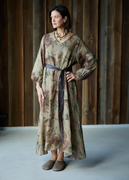 Brązowa sukienka lniana maxi w kwiatowy wzór z długim rękawem i paskiem w talii, luźny fason, styl naturalny i elegancki.