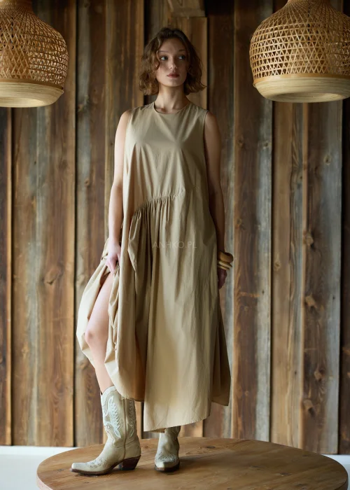 Camelowa sukienka midi o luźnym kroju bez rękawów, z asymetrycznym marszczeniem i rozcięciem, styl casual z kowbojkami.
