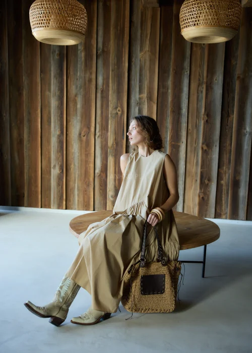 Camelowa sukienka midi o luźnym kroju bez rękawów, z asymetrycznym marszczeniem i rozcięciem, styl casual z kowbojkami.