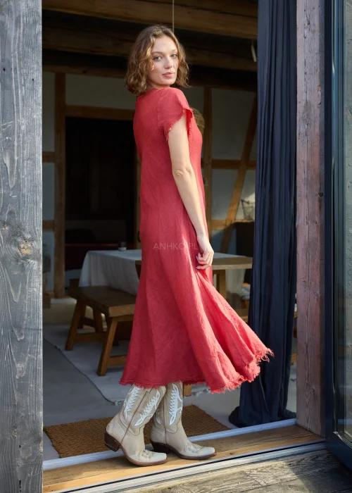 Czerwona lniana sukienka midi o luźnym kroju z krótkim rękawem i surowym wykończeniem, lekko rozkloszowany fason, styl casual z kowbojkami.