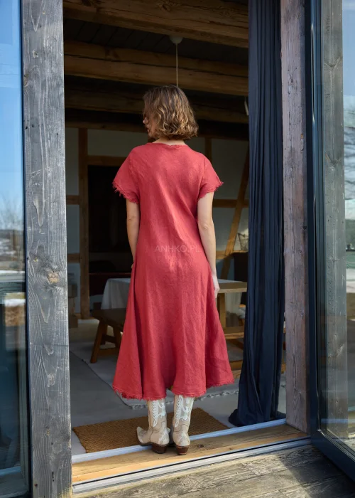 Czerwona lniana sukienka midi o luźnym kroju z krótkim rękawem i surowym wykończeniem, lekko rozkloszowany fason, styl casual z kowbojkami.