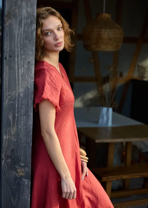 Czerwona lniana sukienka midi o luźnym kroju z krótkim rękawem i surowym wykończeniem, lekko rozkloszowany fason, styl casual z kowbojkami.