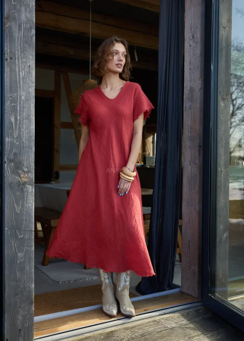 Czerwona lniana sukienka midi o luźnym kroju z krótkim rękawem i surowym wykończeniem, lekko rozkloszowany fason, styl casual z kowbojkami.