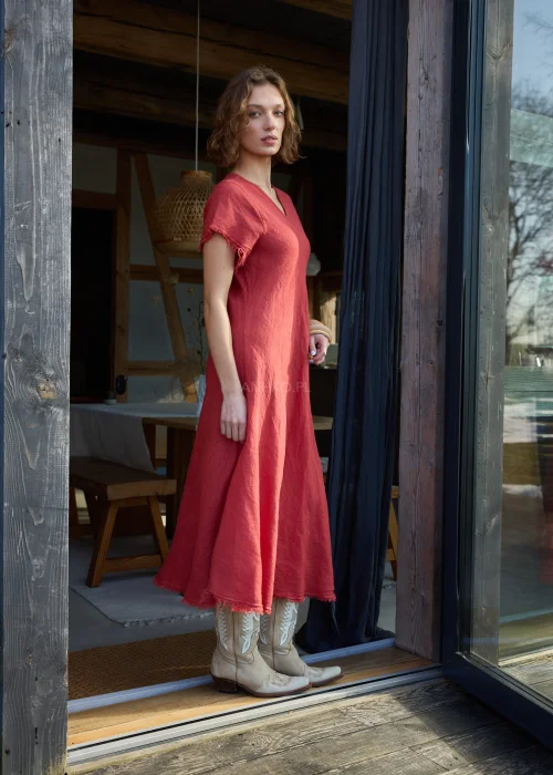 Czerwona lniana sukienka midi o luźnym kroju z krótkim rękawem i surowym wykończeniem, lekko rozkloszowany fason, styl casual z kowbojkami.