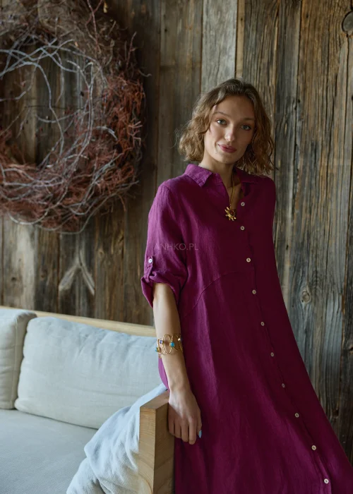 Lniana sukienka koszulowa w kolorze śliwkowym, midi, zapinana na guziki, z kołnierzykiem i podwijanymi rękawami, o luźnym fasonie.