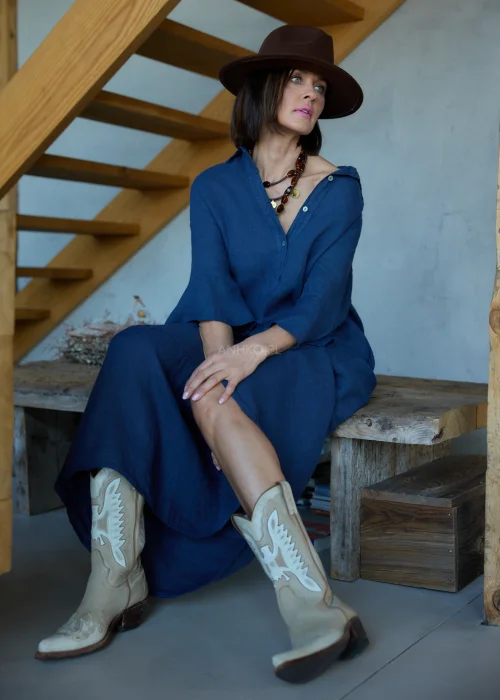 Granatowa lniana sukienka midi o luźnym kroju z kołnierzykiem i guzikami, z falbaną u dołu i rękawem 3/4, styl boho z kapeluszem i kowbojkami.