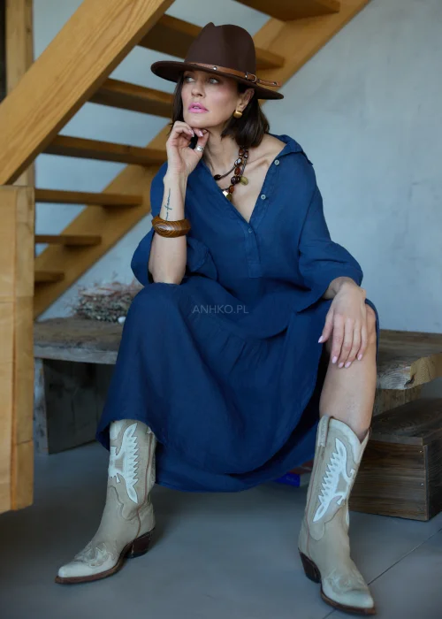 Granatowa lniana sukienka midi o luźnym kroju z kołnierzykiem i guzikami, z falbaną u dołu i rękawem 3/4, styl boho z kapeluszem i kowbojkami.