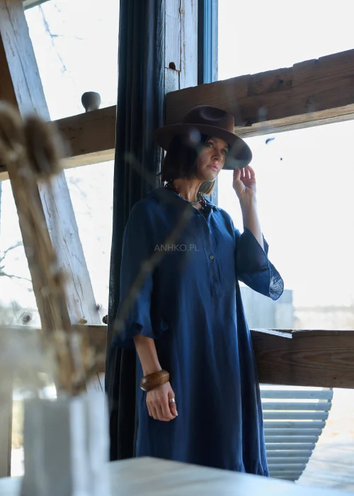 Granatowa lniana sukienka midi o luźnym kroju z kołnierzykiem i guzikami, z falbaną u dołu i rękawem 3/4, styl boho z kapeluszem i kowbojkami.