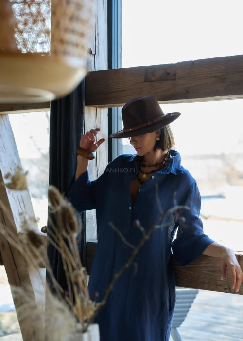 Granatowa lniana sukienka midi o luźnym kroju z kołnierzykiem i guzikami, z falbaną u dołu i rękawem 3/4, styl boho z kapeluszem i kowbojkami.