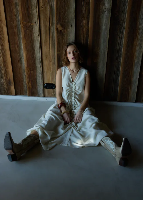 Kremowa sukienka maxi bez rękawów z szerokimi ramiączkami, marszczeniem z przodu i kieszeniami, o luźnym fasonie.