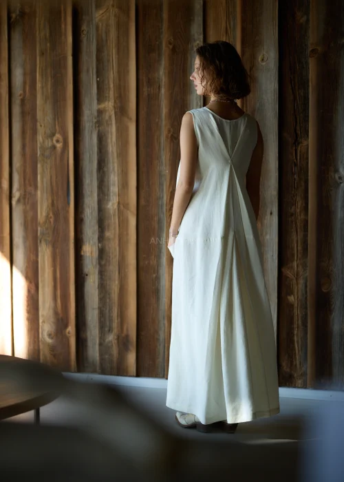 Kremowa sukienka maxi bez rękawów z szerokimi ramiączkami, marszczeniem z przodu i kieszeniami, o luźnym fasonie.