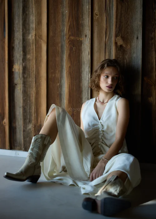 Kremowa sukienka maxi bez rękawów z szerokimi ramiączkami, marszczeniem z przodu i kieszeniami, o luźnym fasonie.