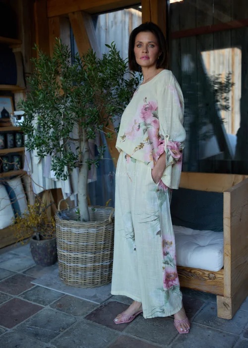 Spodnie damskie w cytrynowym odcieniu z delikatnym kwiatowym printem, o szerokim kroju i elastycznej talii, stylizowane z paskiem i lekką bluzką w naturalnym stylu.