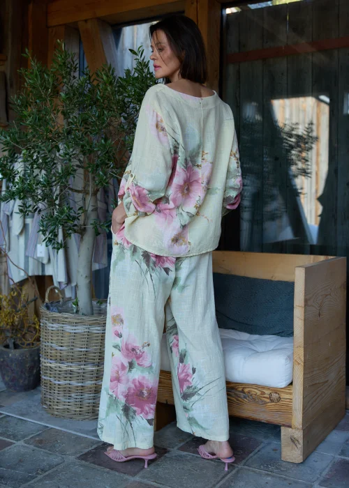 Spodnie damskie w cytrynowym odcieniu z delikatnym kwiatowym printem, o szerokim kroju i elastycznej talii, stylizowane z paskiem i lekką bluzką w naturalnym stylu.