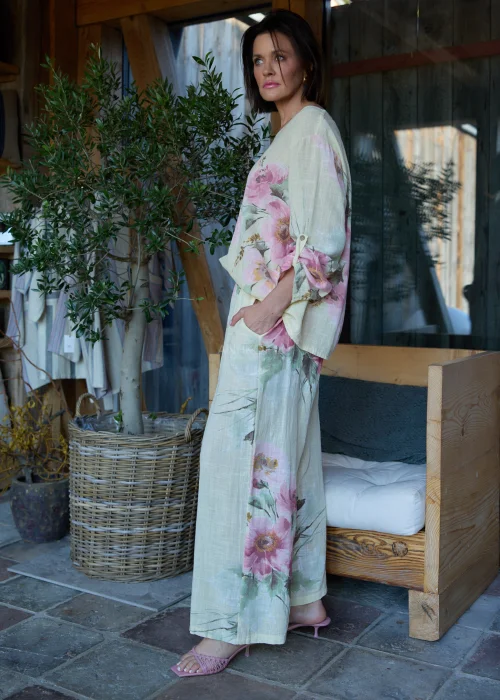 Spodnie damskie w cytrynowym odcieniu z delikatnym kwiatowym printem, o szerokim kroju i elastycznej talii, stylizowane z paskiem i lekką bluzką w naturalnym stylu.