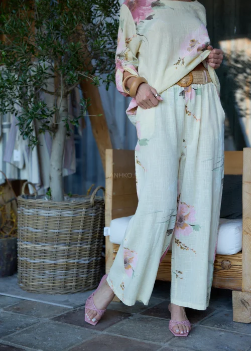 Spodnie damskie w cytrynowym odcieniu z delikatnym kwiatowym printem, o szerokim kroju i elastycznej talii, stylizowane z paskiem i lekką bluzką w naturalnym stylu.