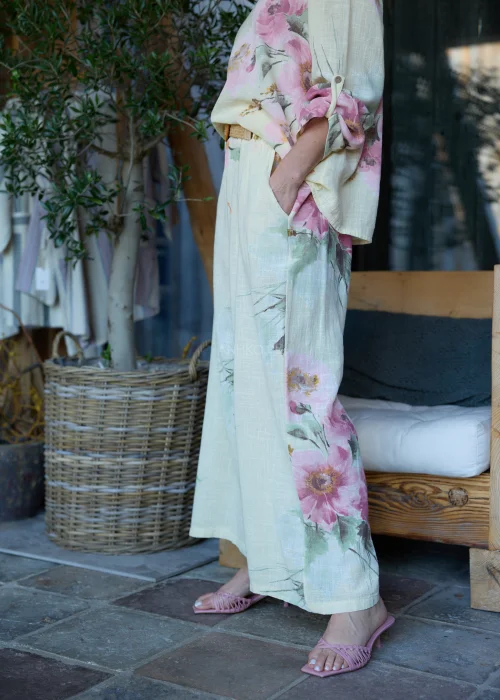 Spodnie damskie w cytrynowym odcieniu z delikatnym kwiatowym printem, o szerokim kroju i elastycznej talii, stylizowane z paskiem i lekką bluzką w naturalnym stylu.