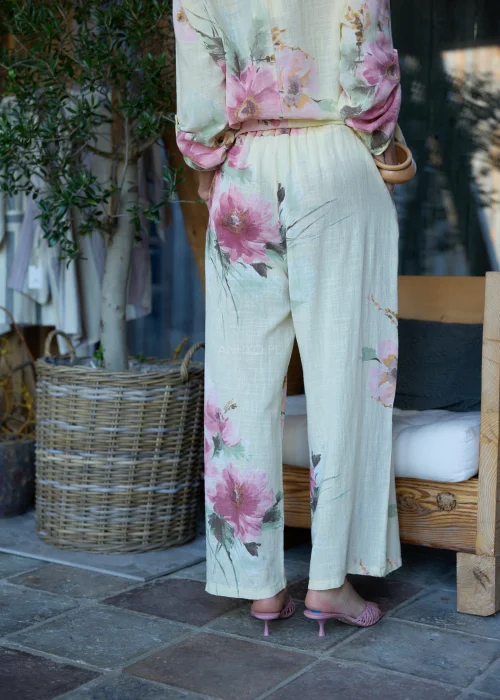 Spodnie damskie w cytrynowym odcieniu z delikatnym kwiatowym printem, o szerokim kroju i elastycznej talii, stylizowane z paskiem i lekką bluzką w naturalnym stylu.